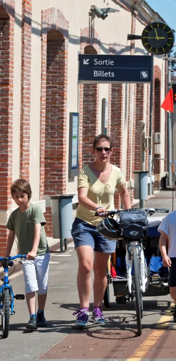 Une famille à vélo dans une gare normande