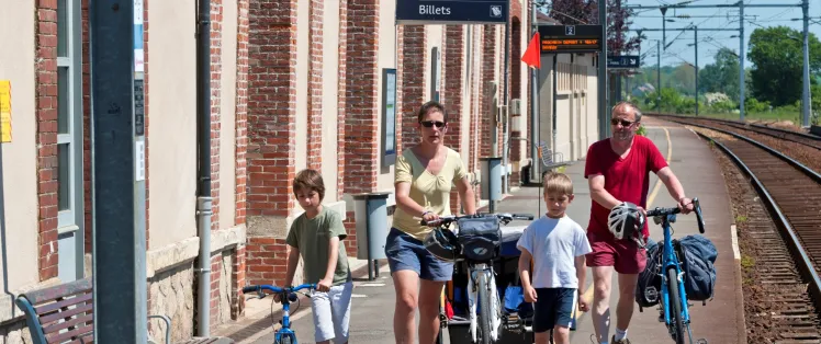 Une famille à vélo dans une gare normande