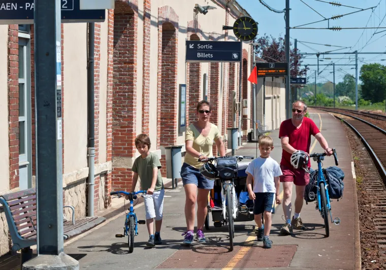 Une famille à vélo dans une gare normande